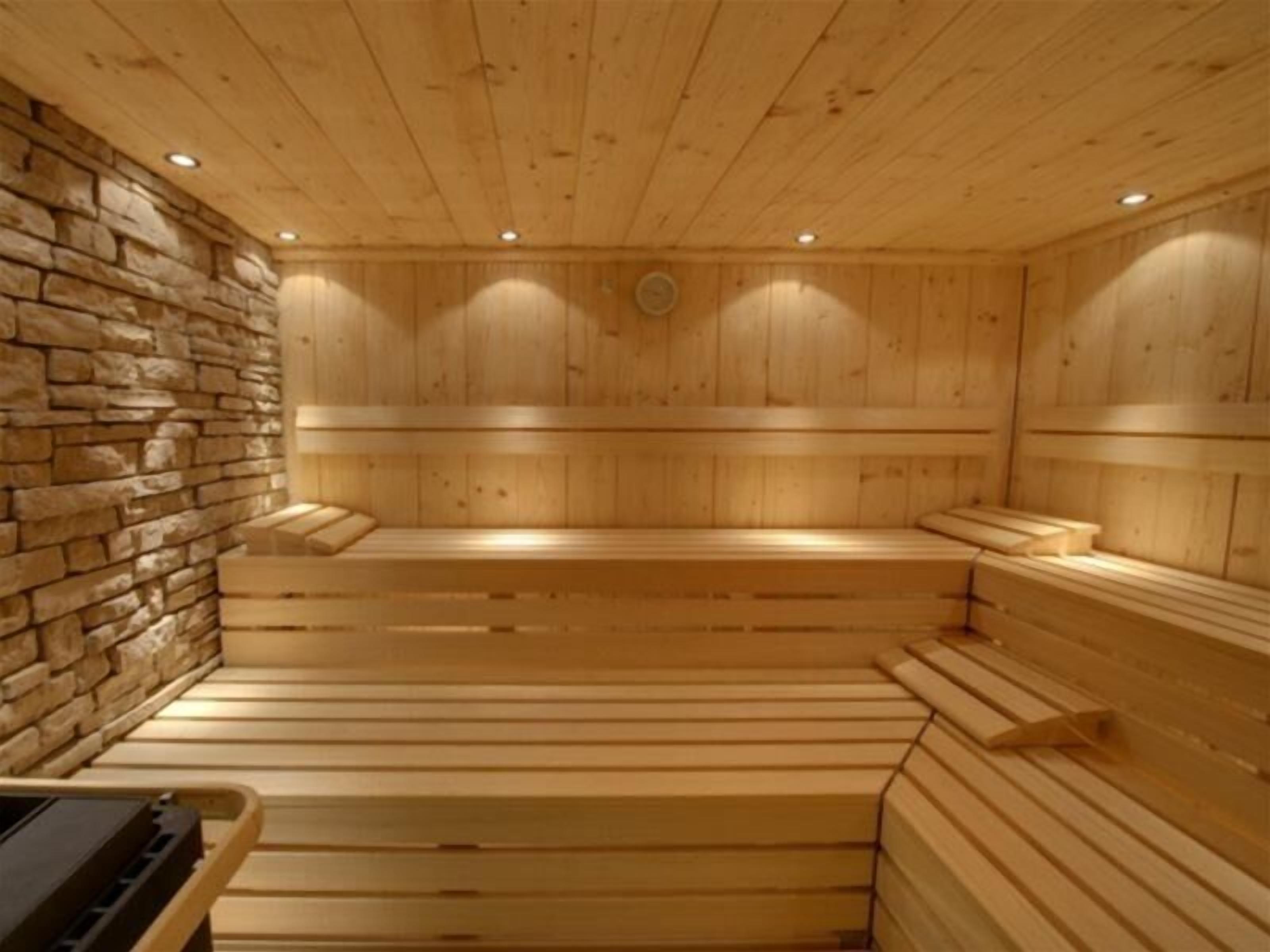 A wooden sauna with benches and a stone wall.