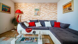 A modern living room with a sectional sofa, a glass coffee table, and a red floor lamp.