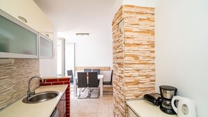 A modern kitchen with a stone accent wall, a built-in dishwasher, a coffee maker, and a dining area with a table and chairs.