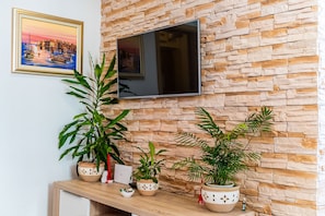 Relax in this stylish living space with a flat-screen TV, potted plants, and a beautiful coastal painting.