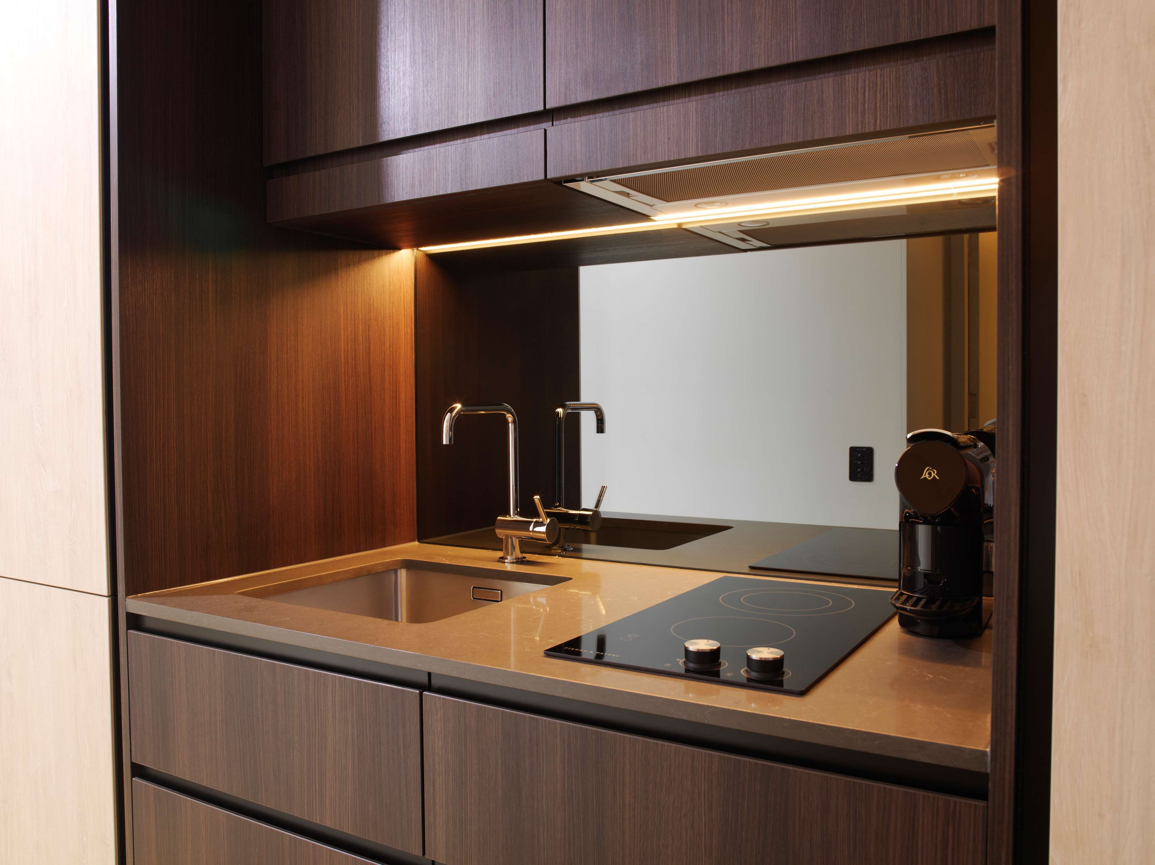 A modern kitchen with a built-in stove, a sink, and a coffee machine.