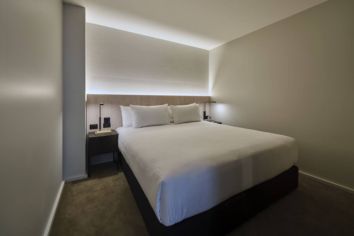 Une chambre d’hôtel moderne avec un grand lit, une table de chevet et une petite table d’appoint.