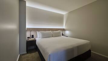 Een moderne hotelkamer met een groot bed, een nachtkastje en een bijzettafeltje.
