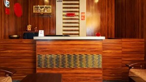 A reception desk with a wooden finish, a small seating area, and a staircase leading to an upper level. - Swarnam Residency (Chennai)