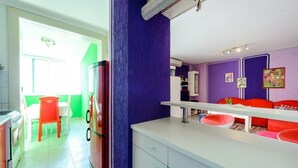 Una cocina con refrigerador, un comedor con mesa y sillas, y una pared morada.