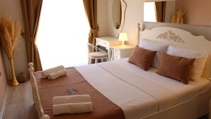 Un lit bien fait, avec des oreillers et des serviettes, une table de chevet avec une lampe, un miroir et une chaise dans une pièce bien éclairée.