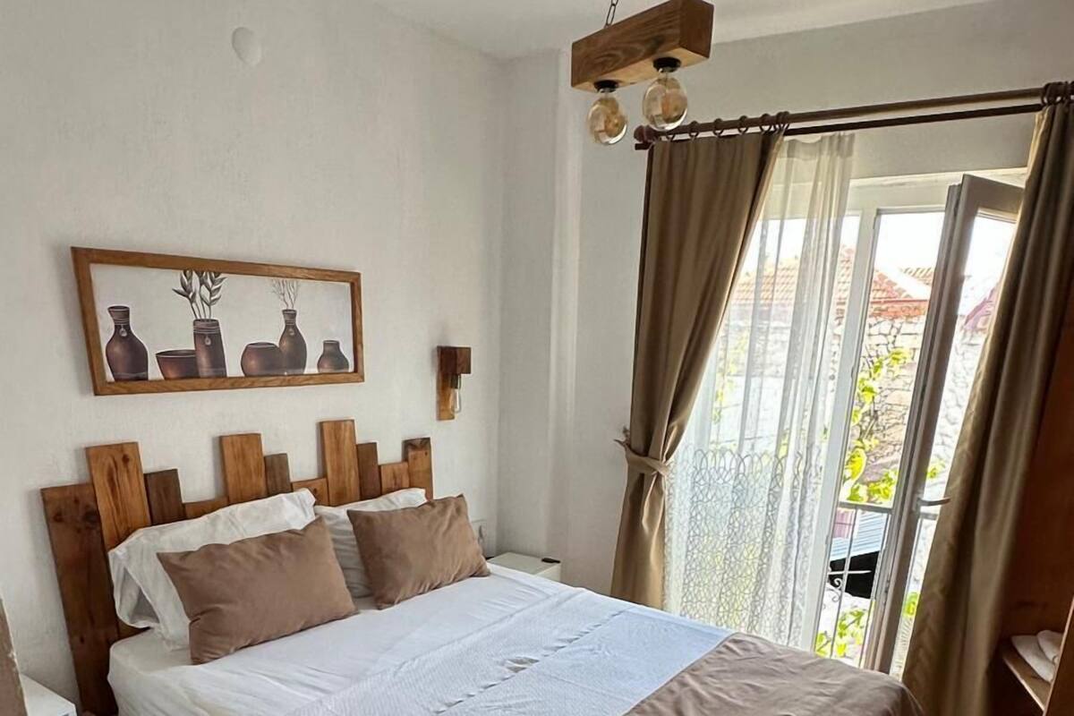 Un dormitorio con cama de madera, un cuadro en la pared y una ventana con cortinas.