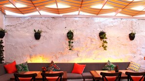 Un restaurant doté d’un mur en pierre rustique, de plantes suspendues et d’un plafond au design moderne.
