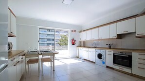 Una cocina moderna con lavadora integrada, un comedor con mesa y sillas, y vistas al exterior.