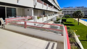 Un moderno edificio de apartamentos con balcón, mobiliario exterior y piscina.