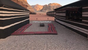 A desert camp with striped tents and a central seating area. - Get Your Night in Wadi Rum (Wadi Rum)