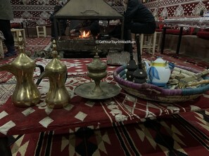 A traditional setting with a central fire, brass water containers, a teapot, and a woven tray with utensils. - Get Your Night in Wadi Rum (Wadi Rum)
