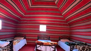 A room with three beds, a central table, and a window. - Get Your Night in Wadi Rum (Wadi Rum)
