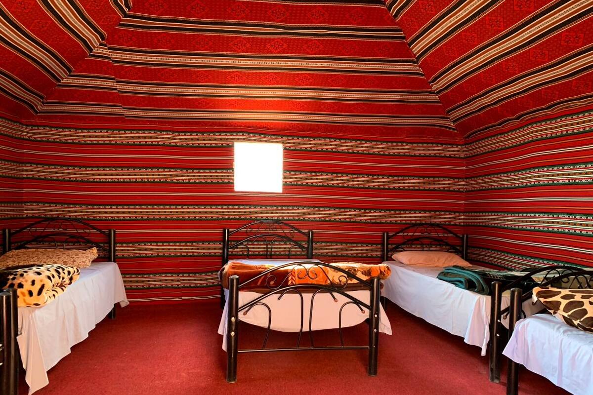 Une chambre avec trois lits, une table et une fenêtre.