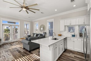 A modern kitchen with white cabinetry, a central island, and a ceiling fan.