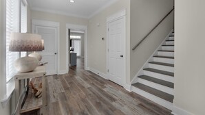 Ein Flur mit Holzboden, weißen Türen und einer Holztreppe.