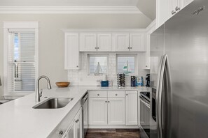 Una cocina moderna con armarios blancos, electrodomésticos de acero inoxidable y una isla grande con un lavamanos.