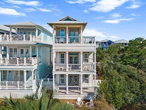 A multi-story beachfront property with balconies, a covered porch, and a view of the ocean.