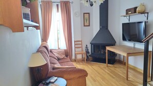 A cozy living room with a sofa, a small table, a TV, a fireplace, and a staircase. - Rural house Majaceite (El Bosque)
