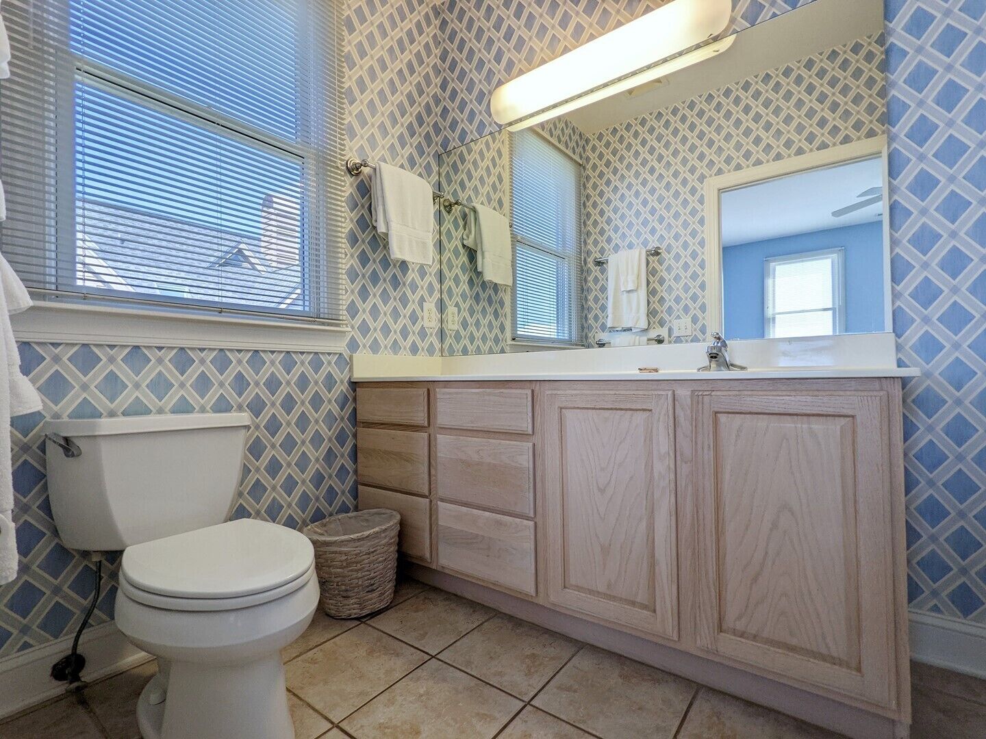 A bathroom with a toilet, a sink with a mirror, and patterned walls.