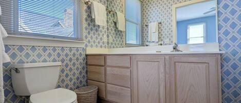 A bathroom with a toilet, a sink with a mirror, and patterned walls.