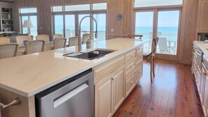 A kitchen with a large island, wooden walls, and a view of the ocean. - Marlin Spectacular Ocean View, Inlet Point South, Beach, Pool (Pawleys Island)