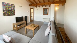 A living room with a sofa set, a wooden coffee table, a TV, and a painting on the wall. - Punta de Vistalegre is a Villa with a Private Pool in a Very Quiet Rural Setting (Porto Cristo)