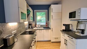A compact kitchen with white cabinets, a toaster, a microwave, and a coffee maker. - DHH "lütte Sprotte" (St. Peter-Ording)