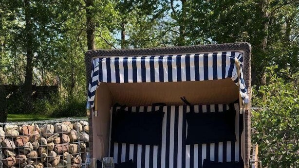 A wooden deck chair with striped cushions and a glass of wine. - DHH "lütte Sprotte" (St. Peter-Ording)