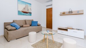 A modern living room with a beige sofa, a glass coffee table, and a wooden sideboard with decorative items.