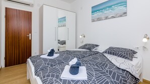 A bedroom with a bed, two bedside tables, a wardrobe, and a painting of the ocean.