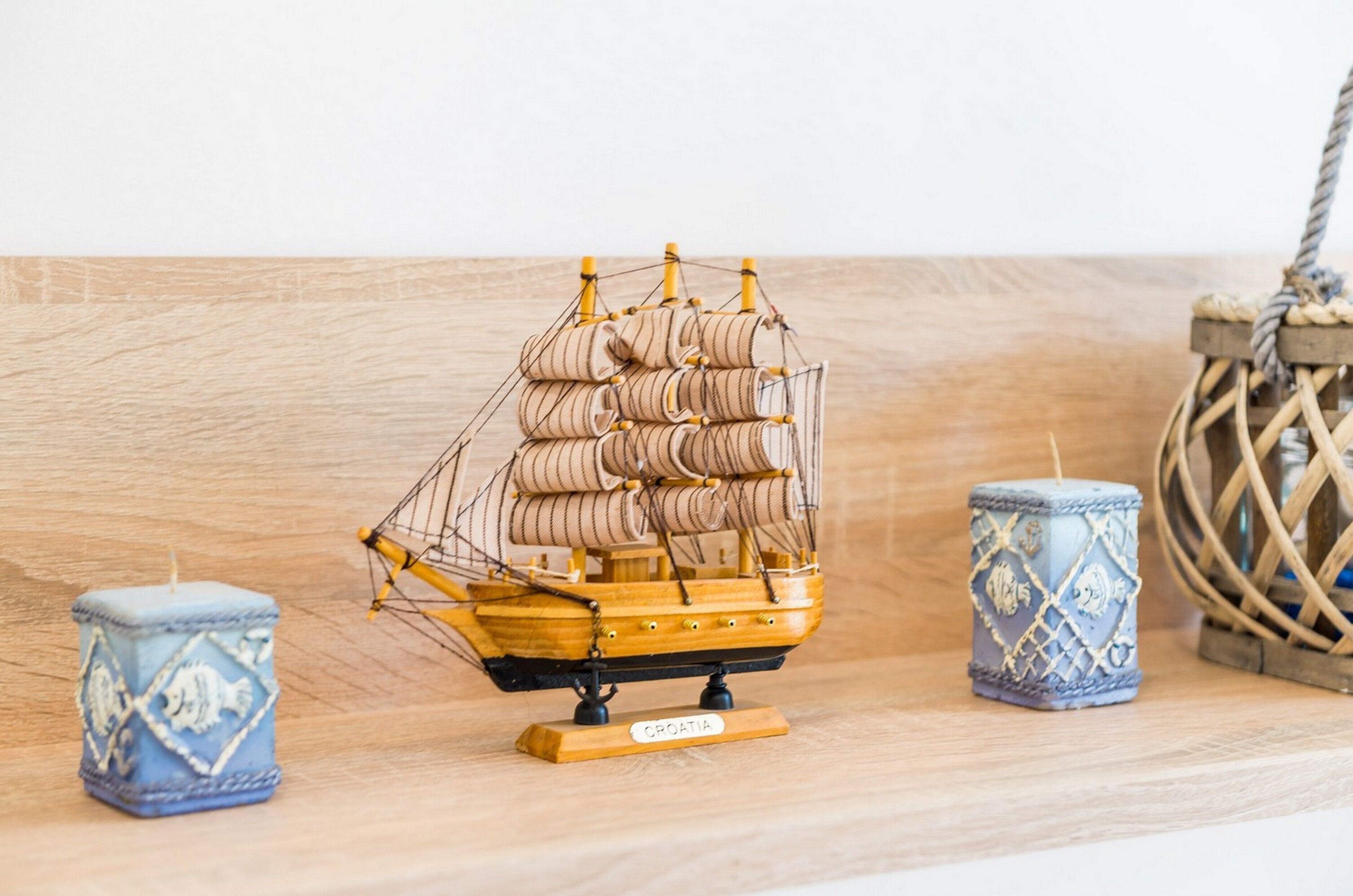 A model ship on a wooden base labeled "CROATIA" with two decorative candles on either side.