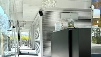 Un couloir moderne aux murs de verre, un comptoir d’accueil noir et un plafond orné d’un luminaire aux formes géométriques.