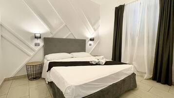 Ett modernt hotellrum med en stor säng, två sängbord, ett runt sidobord och en väggmonterad lampa.
