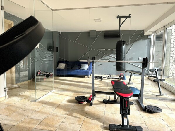 A home gym with a pull-up bar, bench press, and various weights. - Le Village Sarzana (Sarzana)