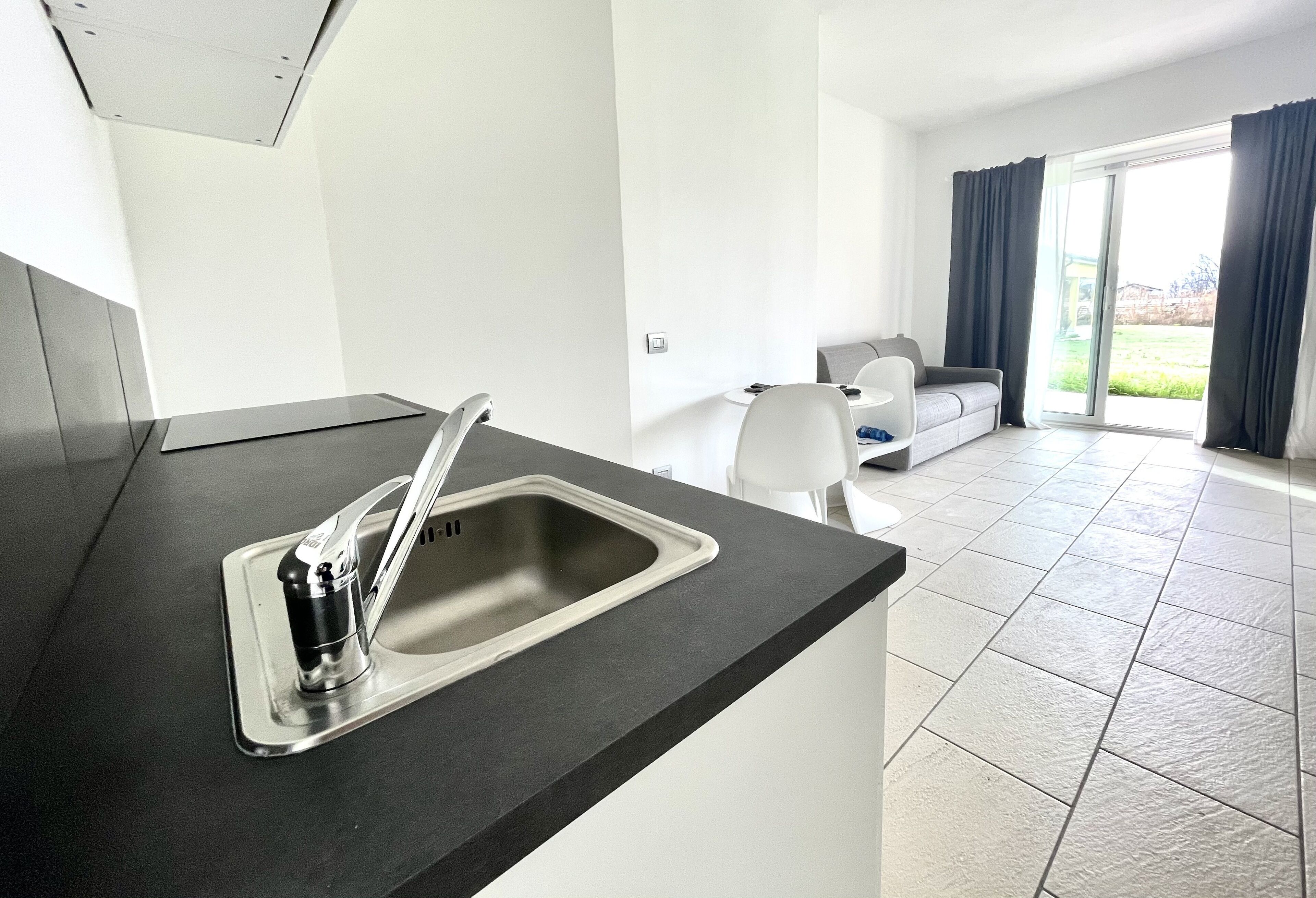 A modern kitchen with a stainless steel sink and a dining area with a white table and chairs.