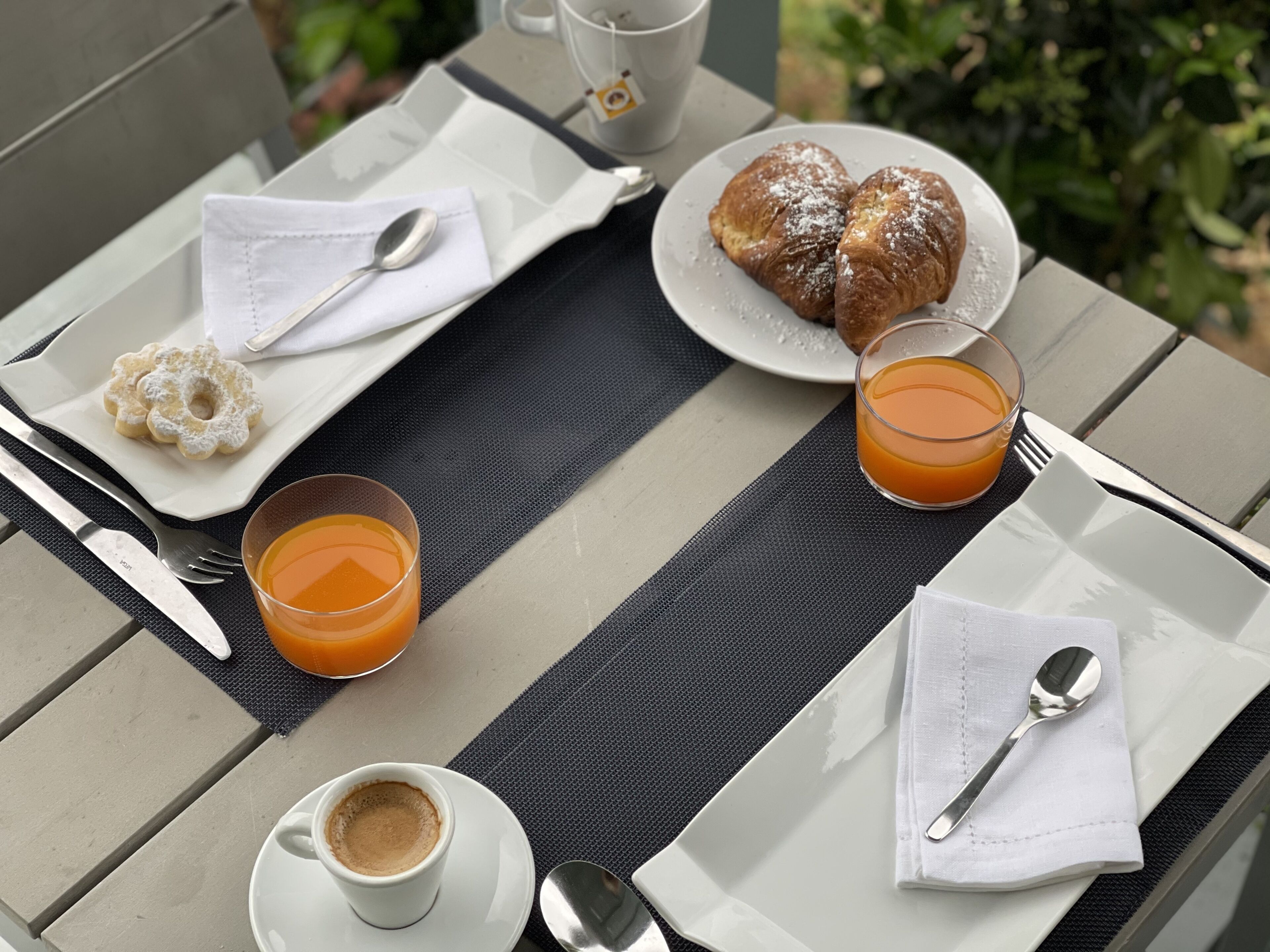 A table set with breakfast items including croissants, a glass of orange juice, a cup of coffee, and a plate of donuts.