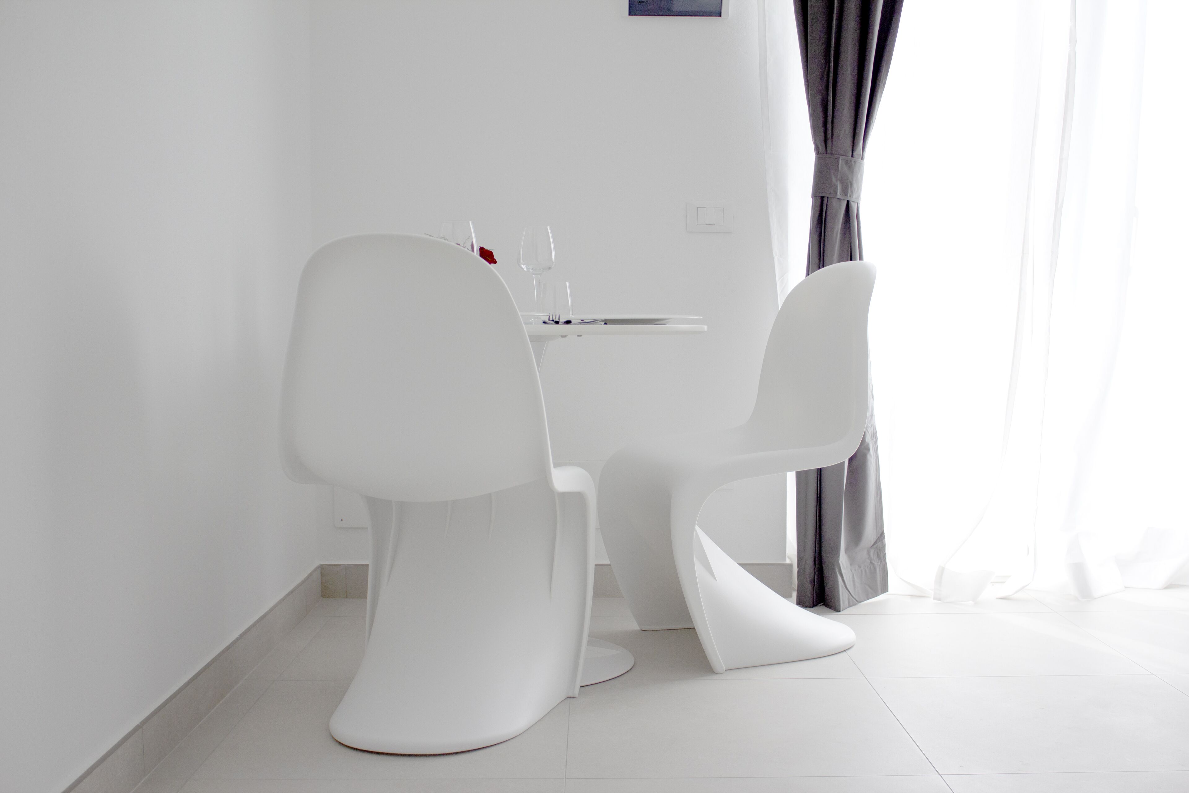 A modern, minimalist dining area with white chairs and a table, featuring a simple, clean design.