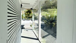 Un edificio moderno con fachada de vidrio, piso de baldosas y vistas al exterior con vegetación.