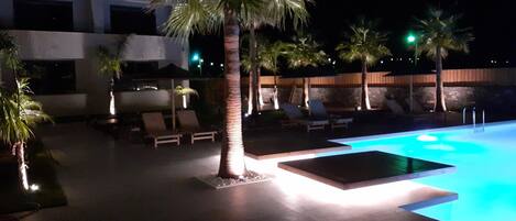 A swimming pool area with lounge chairs and palm trees.