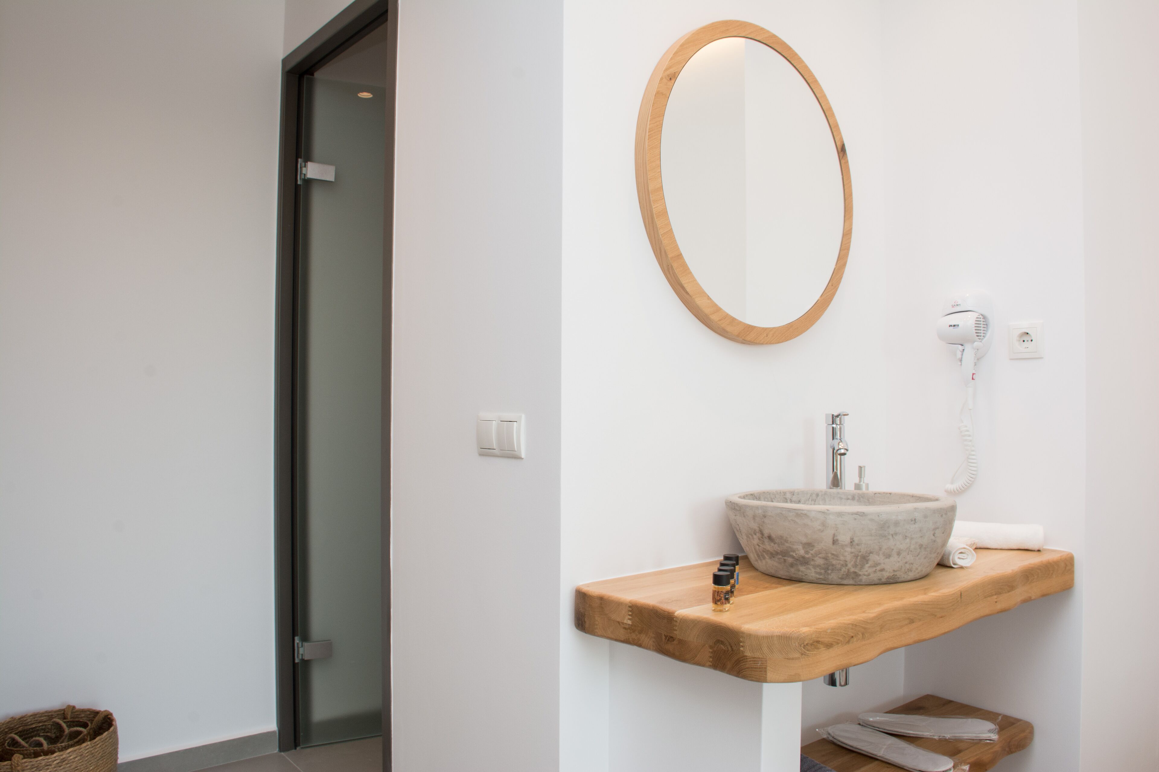 A bathroom with a wooden vanity, a stone sink, a mirror, a hairdryer, and a towel.
