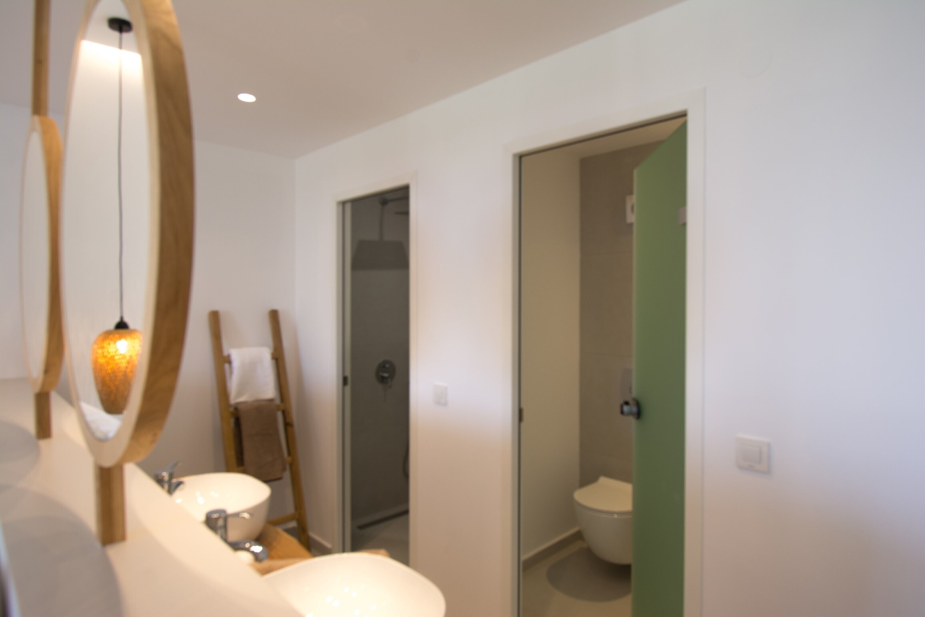 Un baño con un espejo grande, un lavamanos y un inodoro.