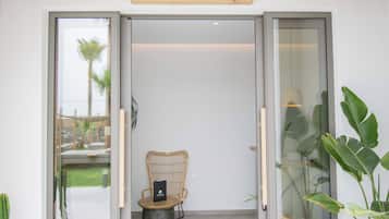 A reception area with a sign above the door, a wicker chair, and a potted plant.