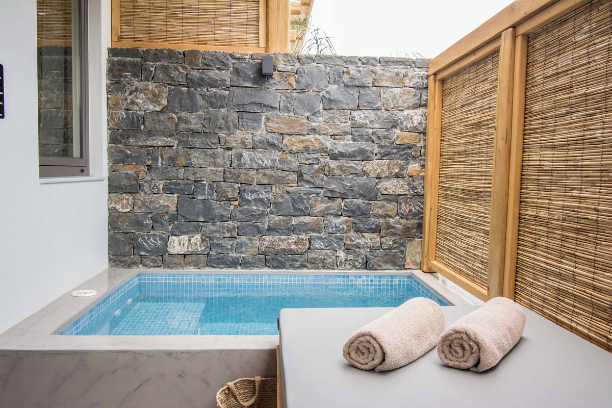 Un espace de détente avec un mur en pierre, une piscine et deux serviettes posées sur une table.