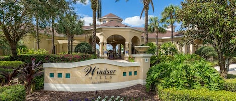 Clubhouse de Windsor Hills amb entrada paisatgística, palmeres i zona de pati coberta.