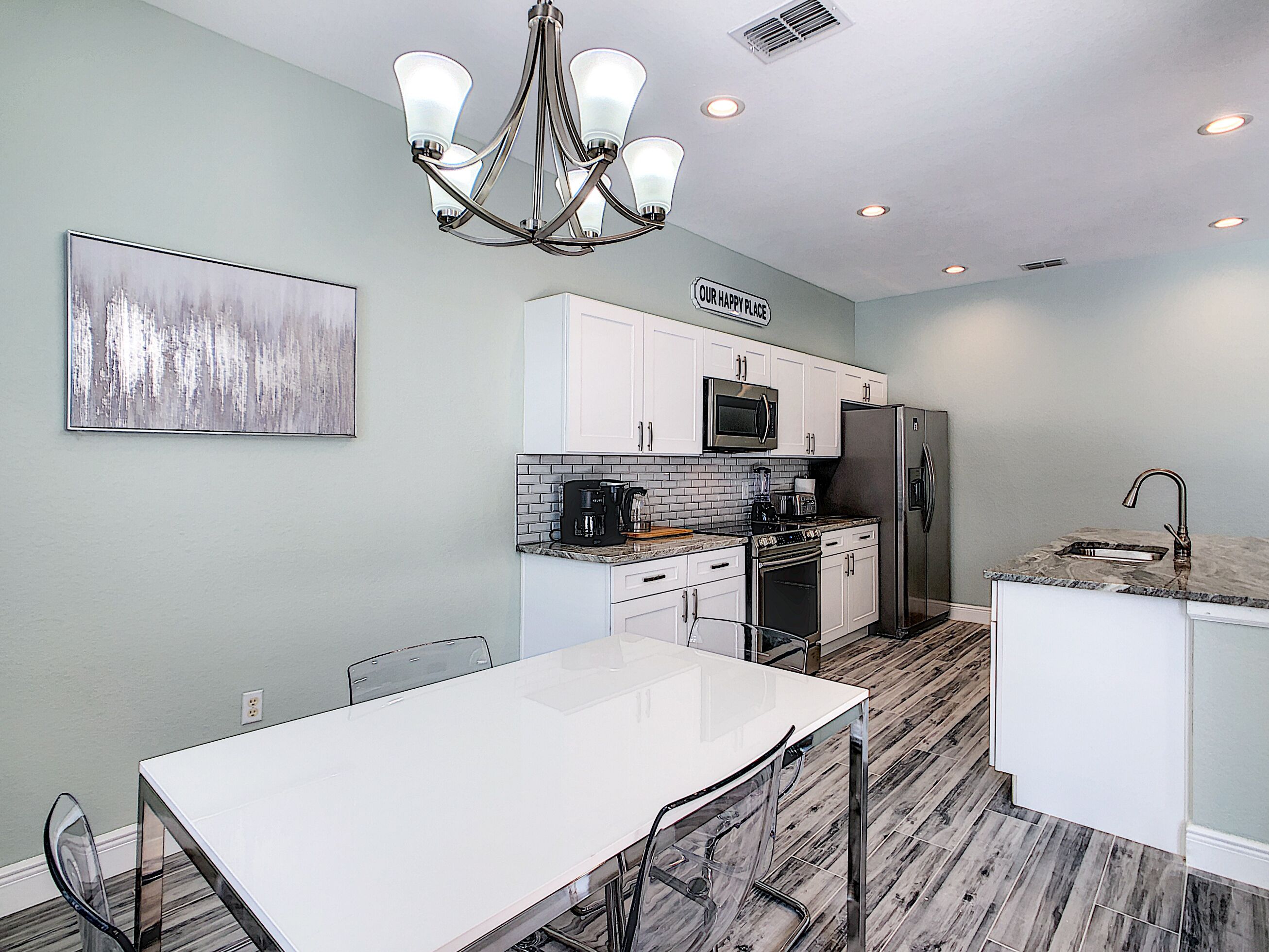 A modern kitchen with white cabinets, a stainless steel refrigerator, a microwave, and a coffee maker.