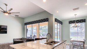 A modern kitchen with a large island, built-in appliances, and a dining area with a view. - 5BR Disney Villa: Pool & Spa, Game Room, Theater (Kissimmee)