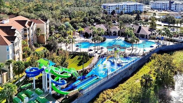 A resort with a large pool, water slides, and a view of surrounding buildings. - 5BR Disney Villa: Pool & Spa, Game Room, Theater (Kissimmee)
