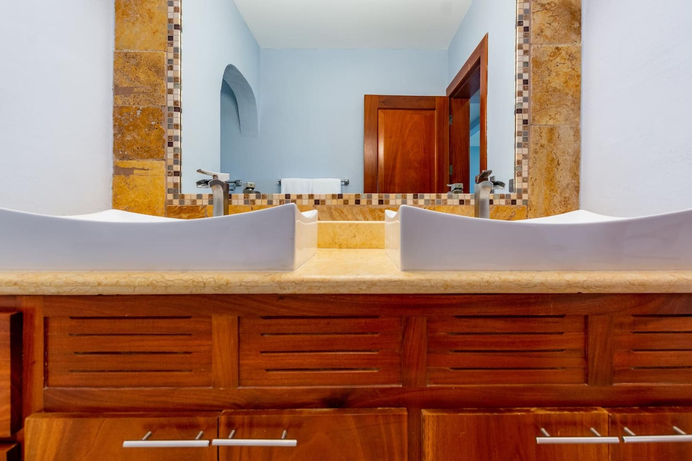 A bathroom with two sinks, a mirror, and a wooden vanity.