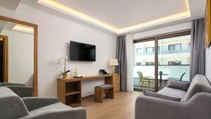 A modern hotel room with a sofa, a desk, a TV, and a balcony with a view. - Hotel Acandia (Rhodes)